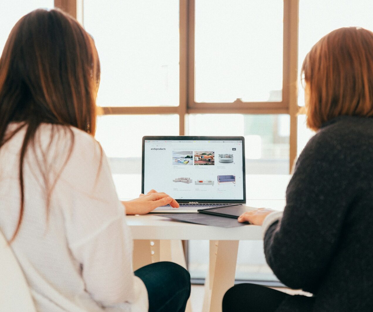 two women talking while looking at laptop computer