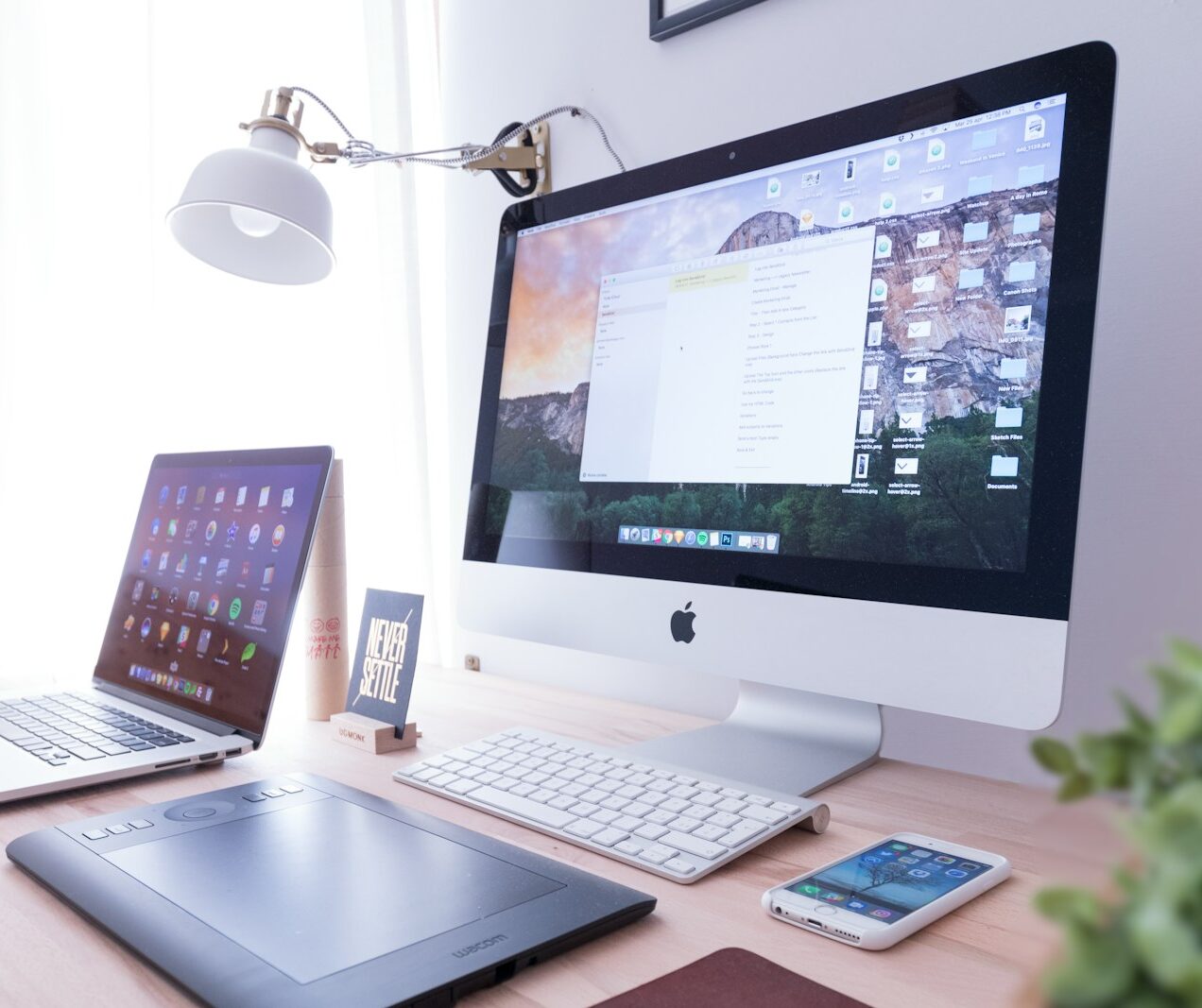 silver iMac near iPhone on brown wooden table
